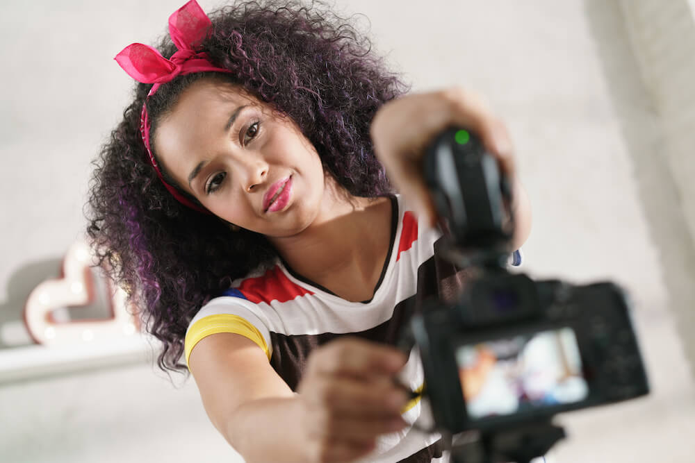 Black woman at home setting up camera and microphone for recording
