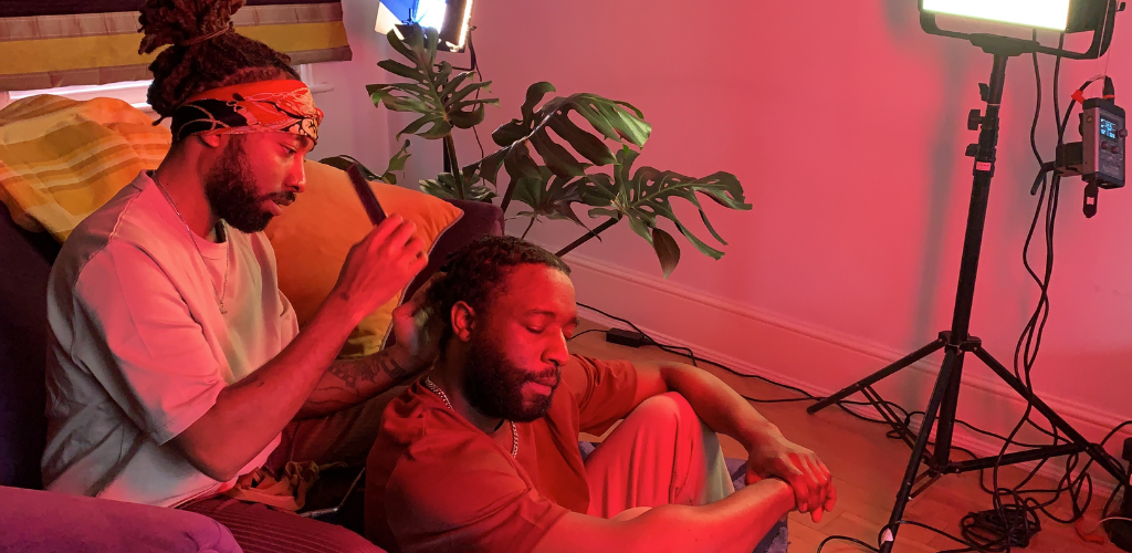 two black male partners sitting on couch being filmed