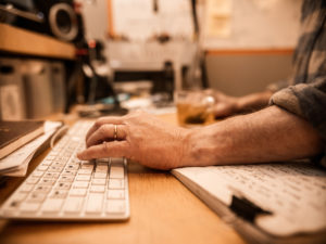 Hand of a man working at his home editing a video using his computer desktop.