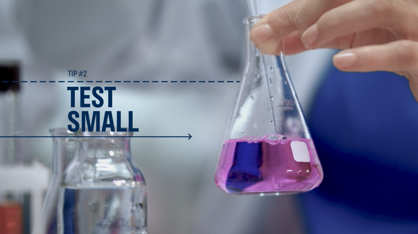 Image of a hand holding a science beaker with pink liquid with dark blue text that reads Tip 2 Test Small. How to use audience testing to improve your videos.