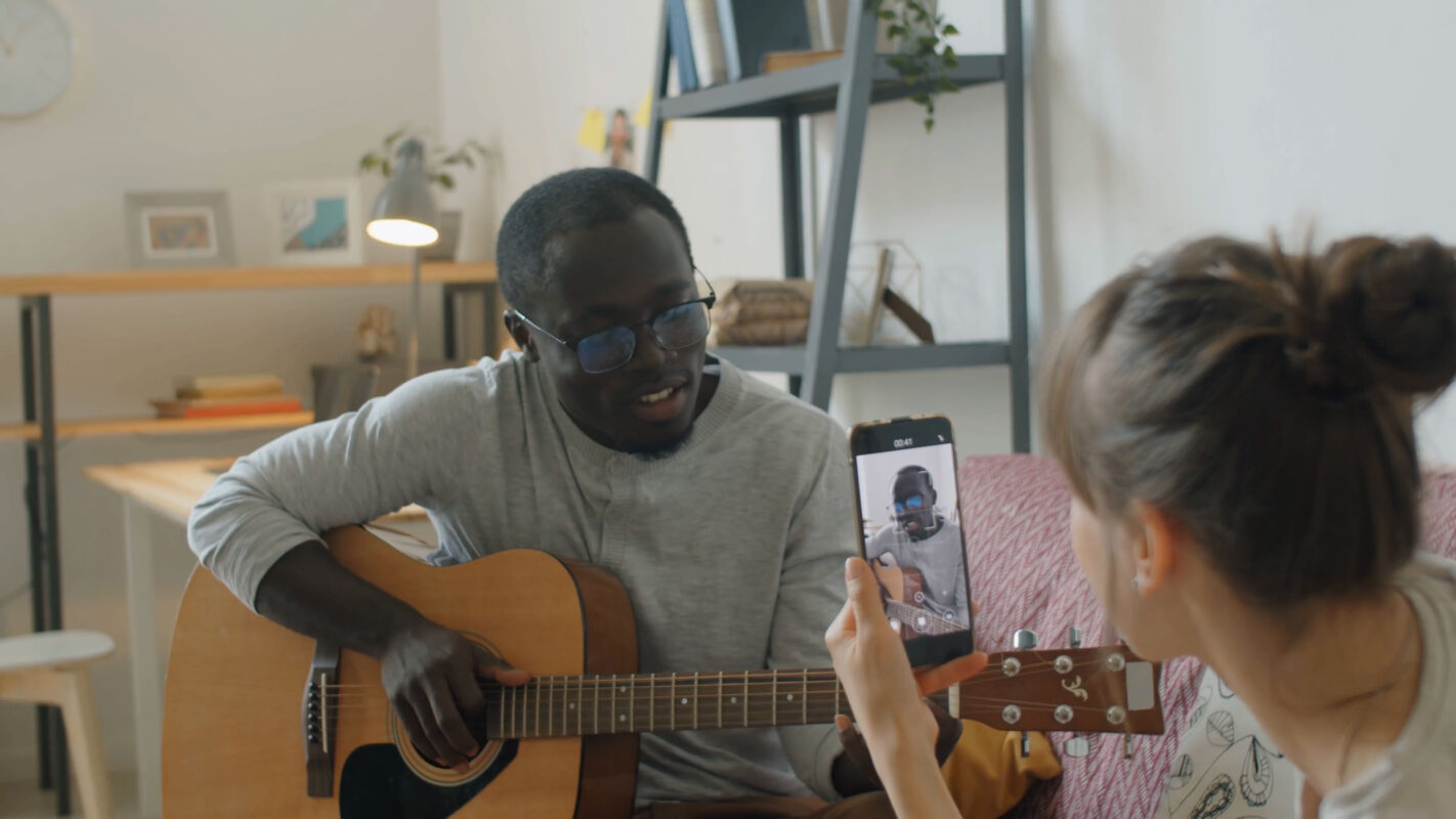 Image of a woman filming a man playing guitar. The evolution of short form video marketing.