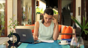 Image of woman reading over a paper with a laptop to the side. Storyblocks vs Envato Elements